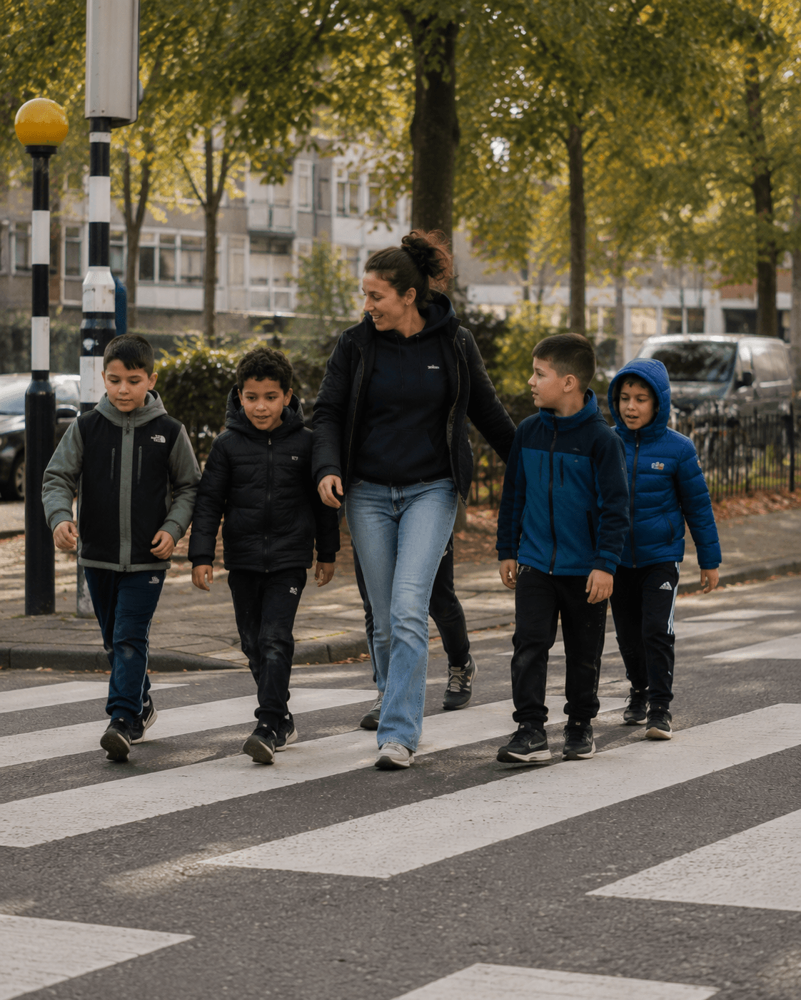 Begeleider steekt samen met een groep jongeren de straat over